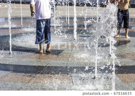Children splashing in the city fountain. Hot summer day. 67816635