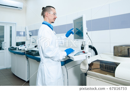 Laboratory assistant in rubber gloves working with 67816733