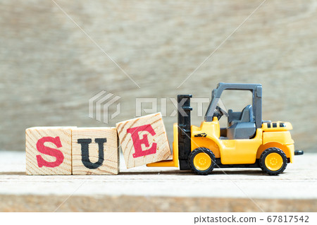 Toy forklift hold letter block e to complete word sue on wood background 67817542
