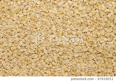 Rolled oats, surface and background. Lightly processed whole-grain food. Husked and steamed oat groats are rolled into flakes and lightly toasted to stabilize them. Food photo, top view, from above. 67818051