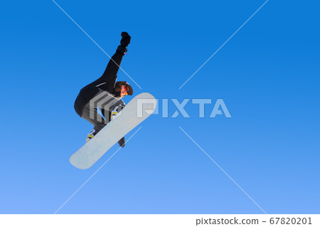 Snowboarder girl does a trick in jumping with a grab against the blue sky. Blue gradient background isolated athlete in flight 67820201