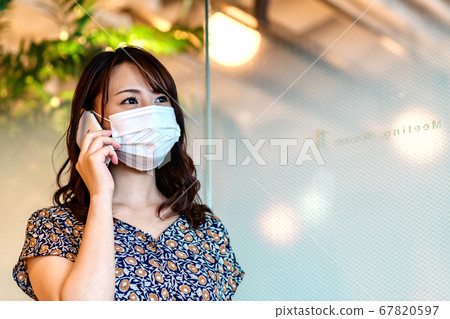 Woman with mask calling in the office 67820597