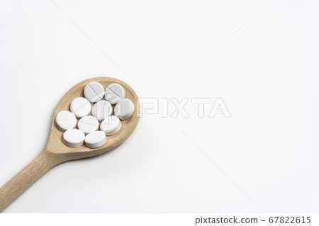 Wooden spoon with tablets on white background Wooden spoon with tablets on white background 67822615