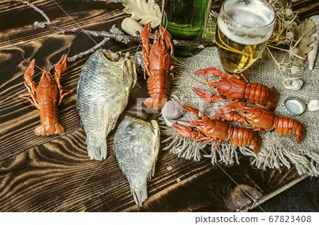 Half-empty glass with beer and a bottle of beer and salted boiled red crayfish   67823408