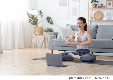 Positive yoga girl doing morning practice in front of laptop Positive yoga girl doing morning practice in front of laptop 67823510