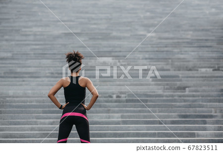 Start training. Girl in sportswear looks at big gray city stair Start training. Girl in sportswear looks at big gray city stair 67823511