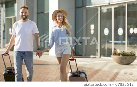 Happy two tourists walking in airport with luggage Happy two tourists walking in airport with luggage 67823512