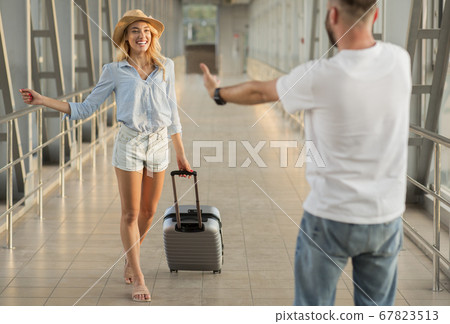 Man picking up his girlfriend at the airport building Man picking up his girlfriend at the airport building 67823513