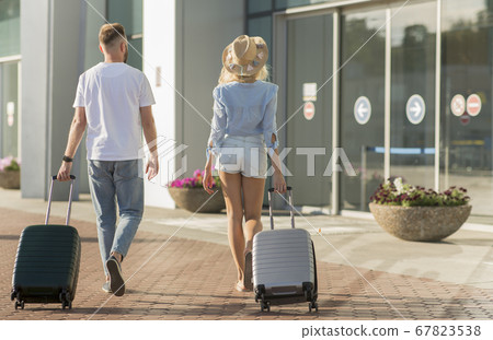 Tourists walking with baggage to the airport terminal Tourists walking with baggage to the airport terminal 67823538