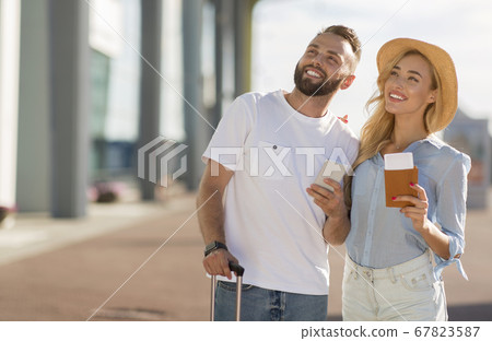 Happy couple standing near airport with their baggage 67823587