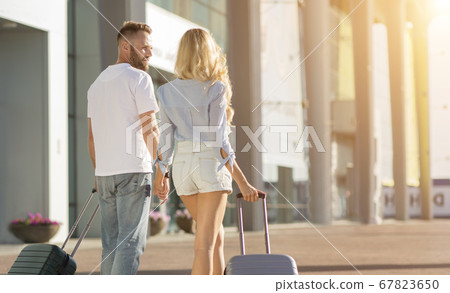 Happy couple walking in airport with valises Happy couple walking in airport with valises 67823650