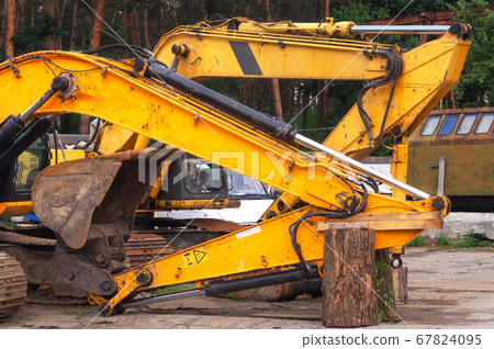 old broken excavator is being repaired. Rusty metal, remnants of old yellow paint, a broken bucket. Repair area. Construction equipment repair concept old broken excavator is being repaired. Rusty metal, remnants of old yellow paint, a broken bucket. Repair area. Construction equipment repair concept 67824095