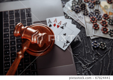Judge wooden gavel and playing cards on computer keyboard, legal rules for online gambling concept 67824441