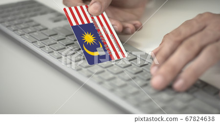 Unknown man pays online with plastic bank card with printed flag of Malaysia. Fictional numbers Unknown man pays online with plastic bank card with printed flag of Malaysia. Fictional numbers 67824638