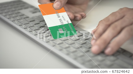 Man pays online with plastic bank card with printed flag of the Republic of Ireland. Fictional numbers 67824642