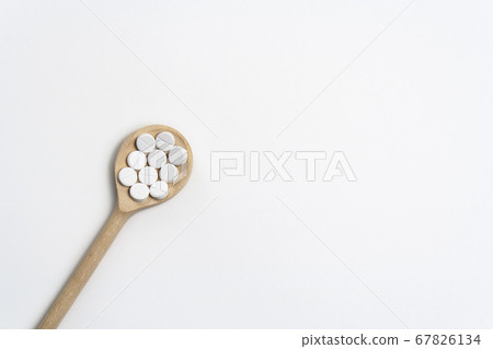 Wooden spoon with tablets on white background 67826134