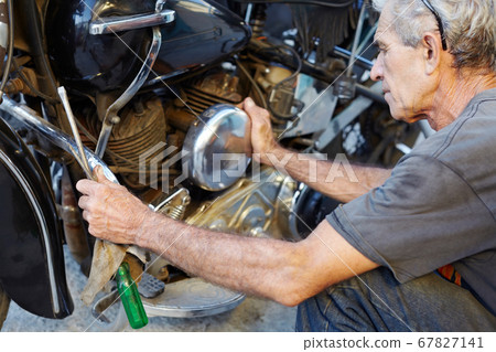 Senior Man Examining His Motorcycle And Fixing Engine 67827141