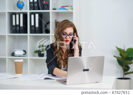 Pretty stylish business woman in glasses having business phone conversation at office. Pretty stylish business woman in glasses having business phone conversation at office. 67827651