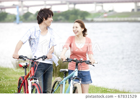 A couple walking while pushing a bicycle A couple walking while pushing a bicycle 67831529