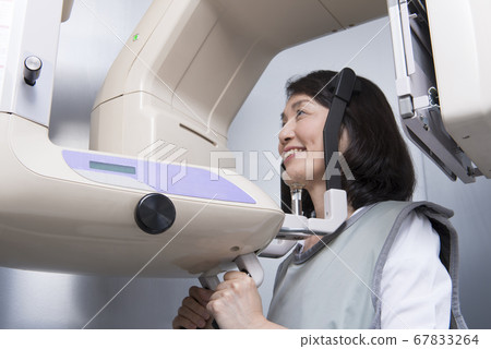A middle-aged woman taking an X-ray of teeth A middle-aged woman taking an X-ray of teeth 67833264