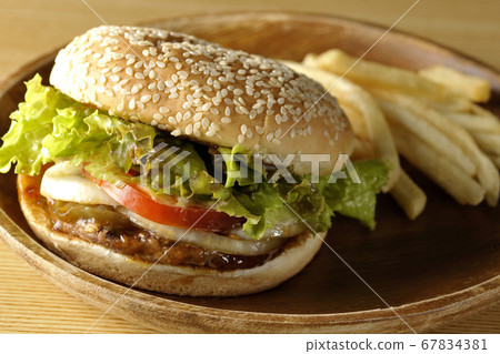 Teriyaki burger and potato fries on a round wooden plate 67834381