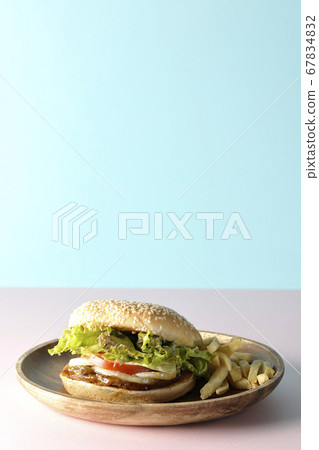 Teriyaki burger and potato fries on a wooden plate taken using two background papers of pink and light blue 67834832