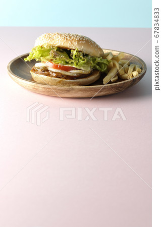 Teriyaki burger and potato fries on a wooden plate taken using two background papers of pink and light blue 67834833