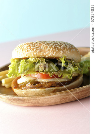 Teriyaki burger and potato fries on a wooden plate taken using two background papers of pink and light blue 67834835