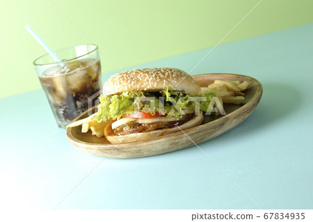 Teriyaki burger, potato fries and cola on a round wooden plate taken using a two color background paper 67834935