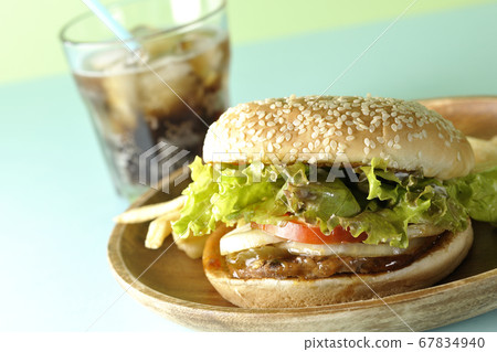 Teriyaki burger, potato fries and cola on a round wooden plate taken using a two color background paper 67834940