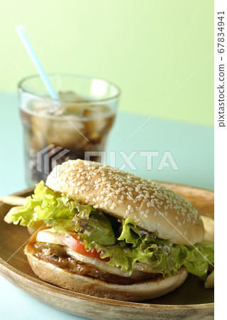 Teriyaki burger, potato fries and cola on a round wooden plate taken using a two color background paper 67834941