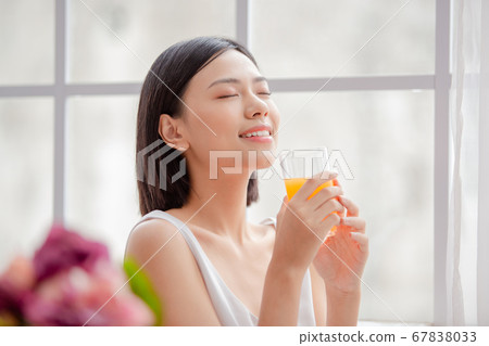 Woman relaxing with juice in one hand Woman relaxing with juice in one hand 67838033