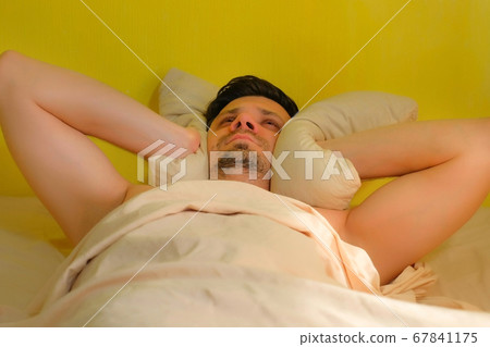 Man can't sleep from noise, covers himself with a pillow. Noisy neighbors. 67841175
