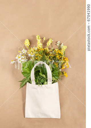 Bouquet of field flowers in fabric eco bag on beige background. Concept no plastic and zero waste. Top view Mockup 67841990