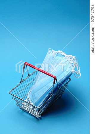 Safe and online shopping on quarantine concept. Shopping basket with protective medical mask over blue background 67842798