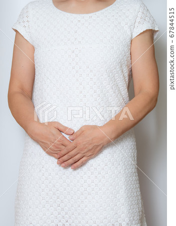 A woman putting her hands on her stomach A woman putting her hands on her stomach 67844515