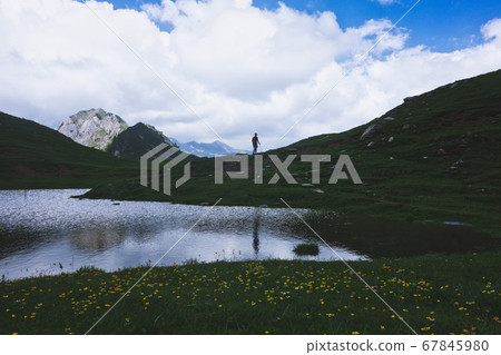 Mountain landscape with small lake and a person Mountain landscape with small lake and a person 67845980