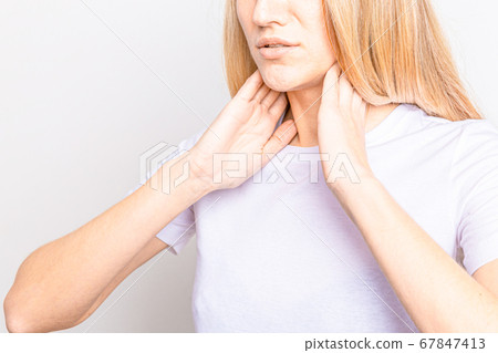 Female checking thyroid gland by herself. Close up of woman in white t- shirt touching neck with red spot. Thyroid disorder includes goiter, hyperthyroid, hypothyroid, tumor or cancer. Health care. Female checking thyroid gland by herself. Close up of woman in white t- shirt touching neck with red spot. Thyroid disorder includes goiter, hyperthyroid, hypothyroid, tumor or cancer. Health care. 67847413