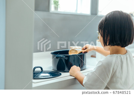 A girl stirs a pot in a clean kitchen girl pot mix A girl stirs a pot in a clean kitchen girl pot mix 67848521