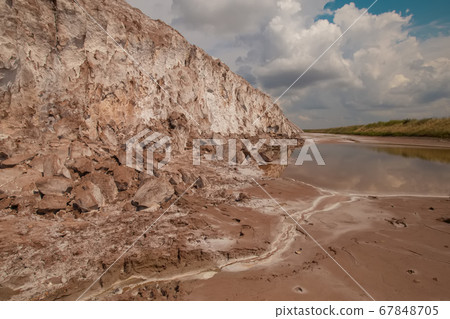 Soligork salt mine slagheap mountains and scenic nature with dramatic cloudy blue sky in summer day. A technical water lake, white salt rock and cracked ground Soligork salt mine slagheap mountains and scenic nature with dramatic cloudy blue sky in summer day. A technical water lake, white salt rock and cracked ground 67848705