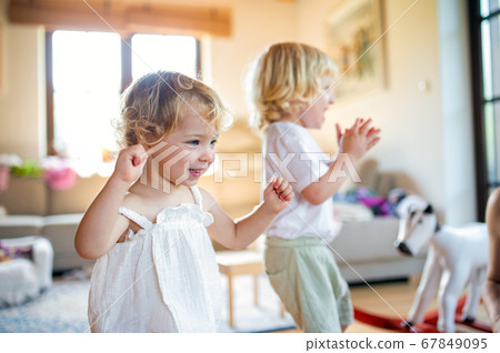 Portrait of small boy and girl playing indoors at home. Portrait of small boy and girl playing indoors at home. 67849095