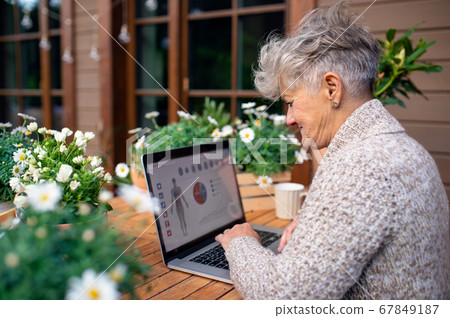 Senior woman with laptop and coffee sitting on terrace in summer, resting. Senior woman with laptop and coffee sitting on terrace in summer, resting. 67849187