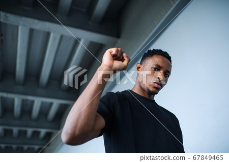 Black man with raised fist standing outdoors in city, black lives matter concept. Black man with raised fist standing outdoors in city, black lives matter concept. 67849465