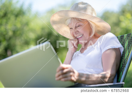 Concentrated elderly woman texting her friends via the laptop Concentrated elderly woman texting her friends via the laptop 67852988