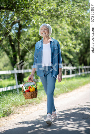 Relaxed woman walking with a basket of vegetable 67853097