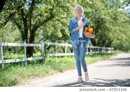 Cheerful senior woman growing vegetables in a countryside Cheerful senior woman growing vegetables in a countryside 67853106