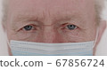 Macro portrait of wrinkled senior man with mask blinks into the camera 67856724