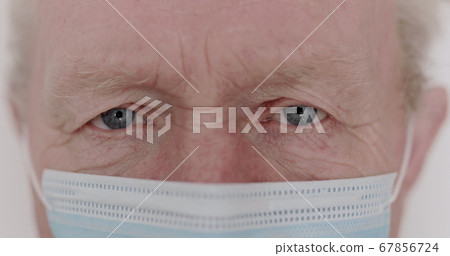 Macro portrait of wrinkled senior man with mask blinks into the camera Macro portrait of wrinkled senior man with mask blinks into the camera 67856724