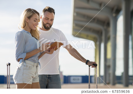Travel concept. Young couple checking tickets outside 67859636