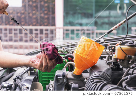 Cars mechanic is checking the level of engine oil. Cars mechanic is checking the level of engine oil. 67861575